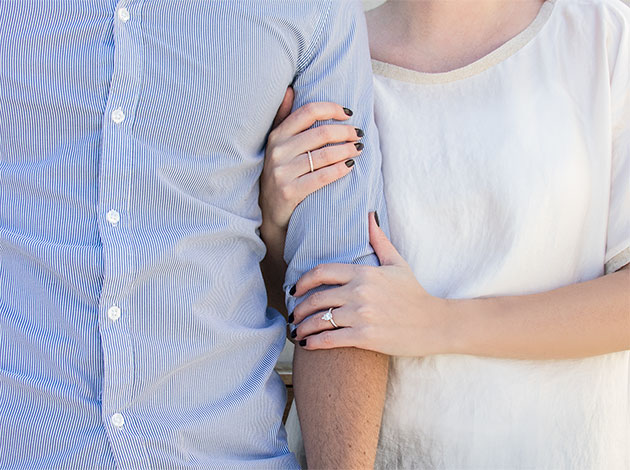 A couple holding hands featuring a solitaire Diamond Nexus engagement ring.