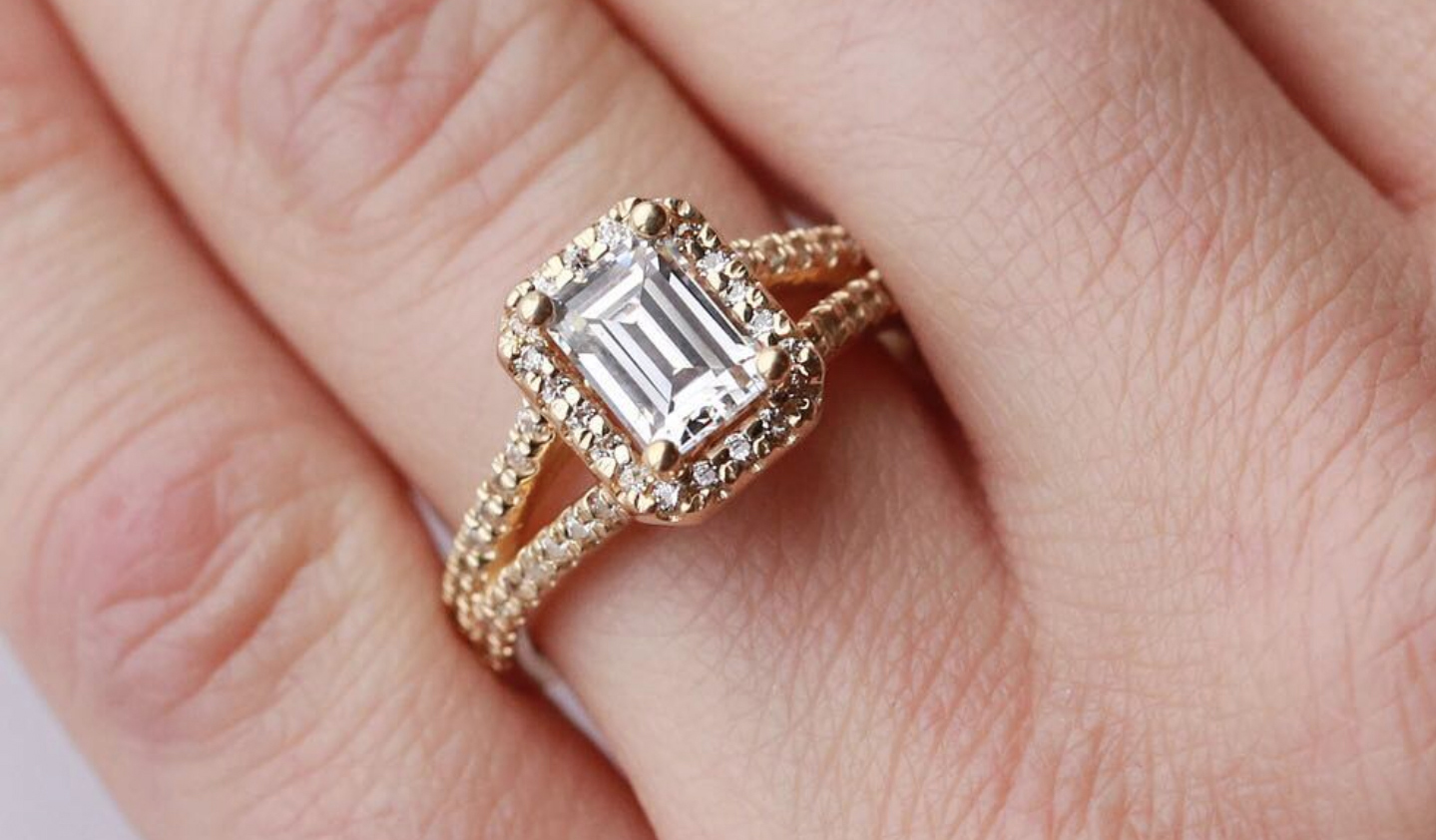  A Diamond Nexus halo Emerald cut engagement ring in yellow gold.