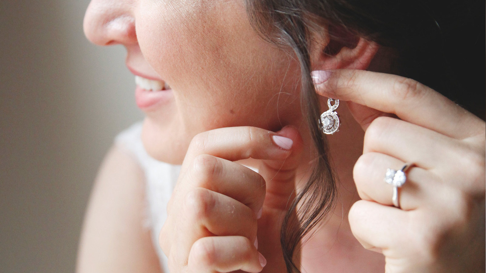 A bride putting on her Diamond Nexus drop earrings.
