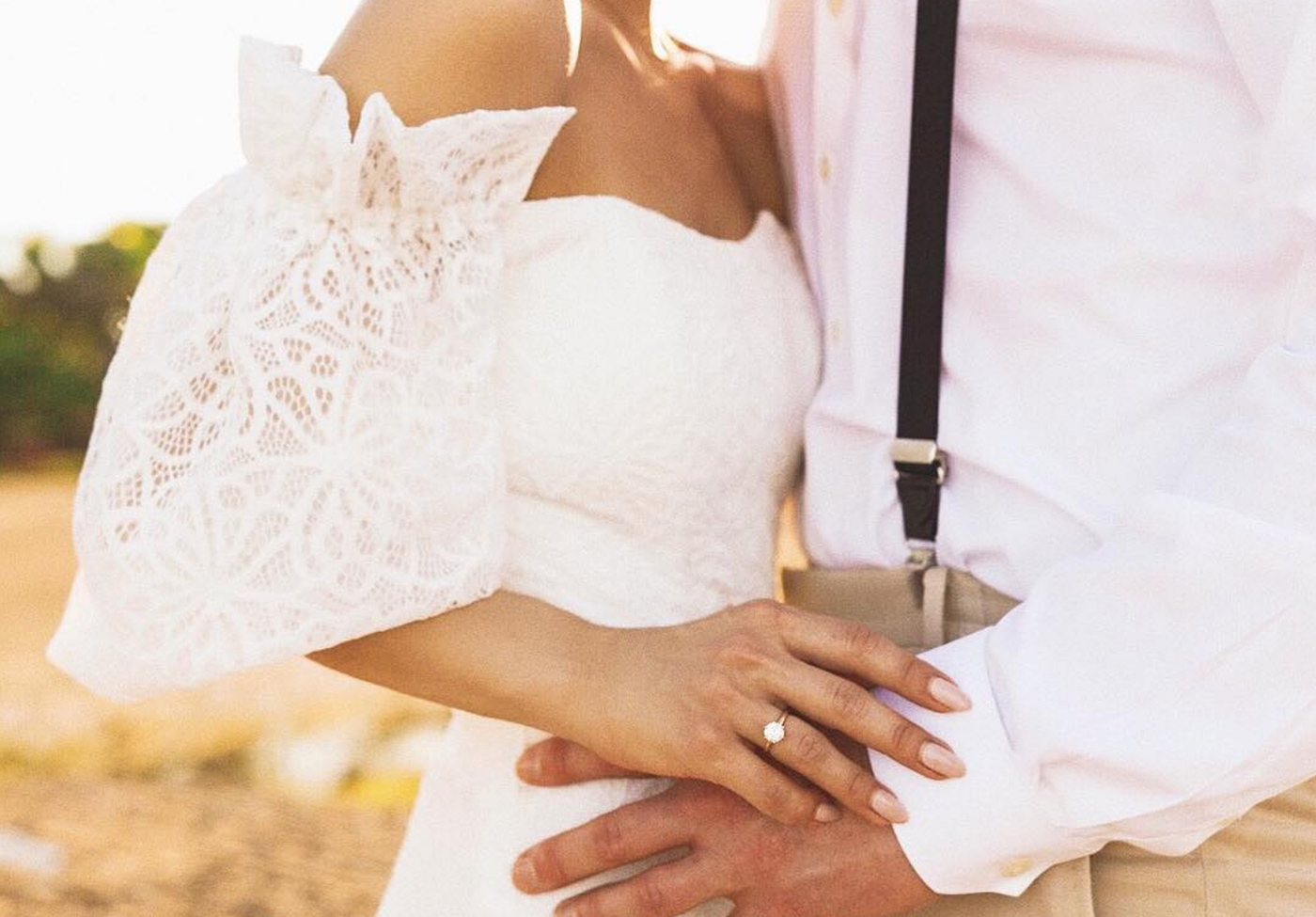 Newlyweds on their wedding day featuring a solitaire Round Brilliant cut engagement ring on the bride.