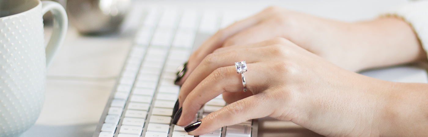 Solitaire engagement ring from Diamond Nexus featured on a hand typing on a keyboard