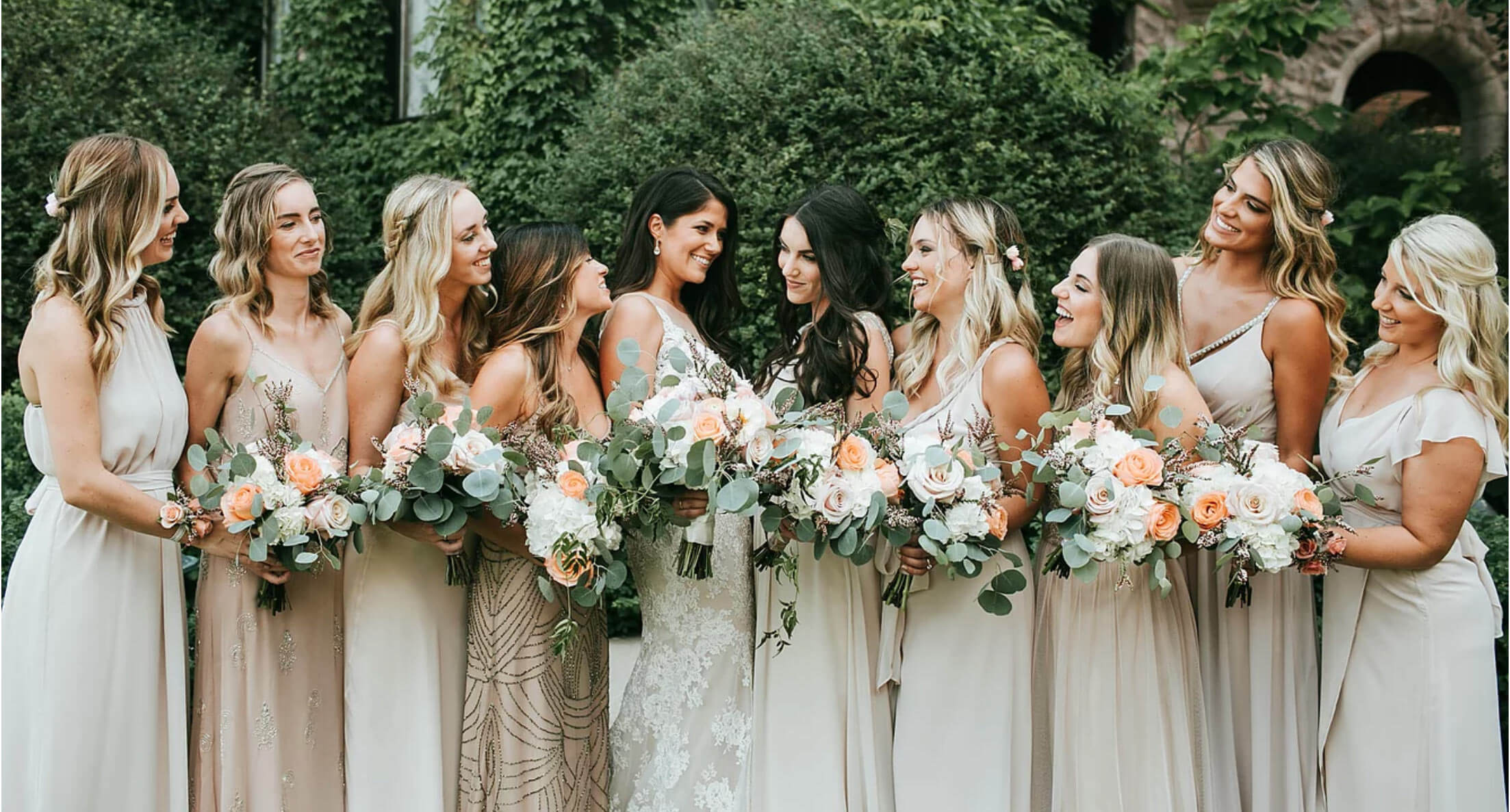 A bridal party holding bouquets admiring the bride.