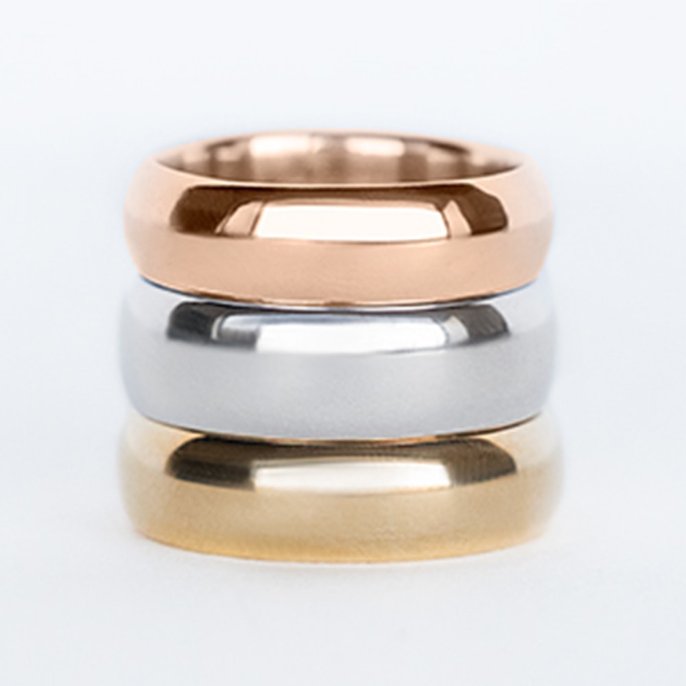 A rose, white and yellow gold wedding band stacked on top of each other.