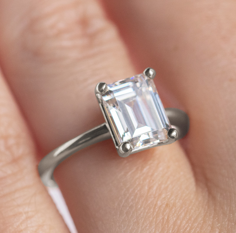 An emerald cut stone fixed to a solitaire band