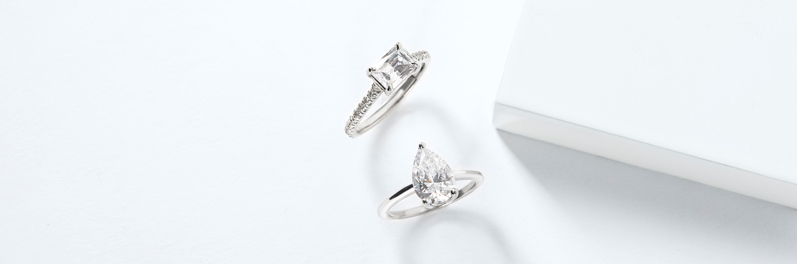 A baguette cut engagement ring with an accented band and a pear cut diamond alternative with a solitaire band