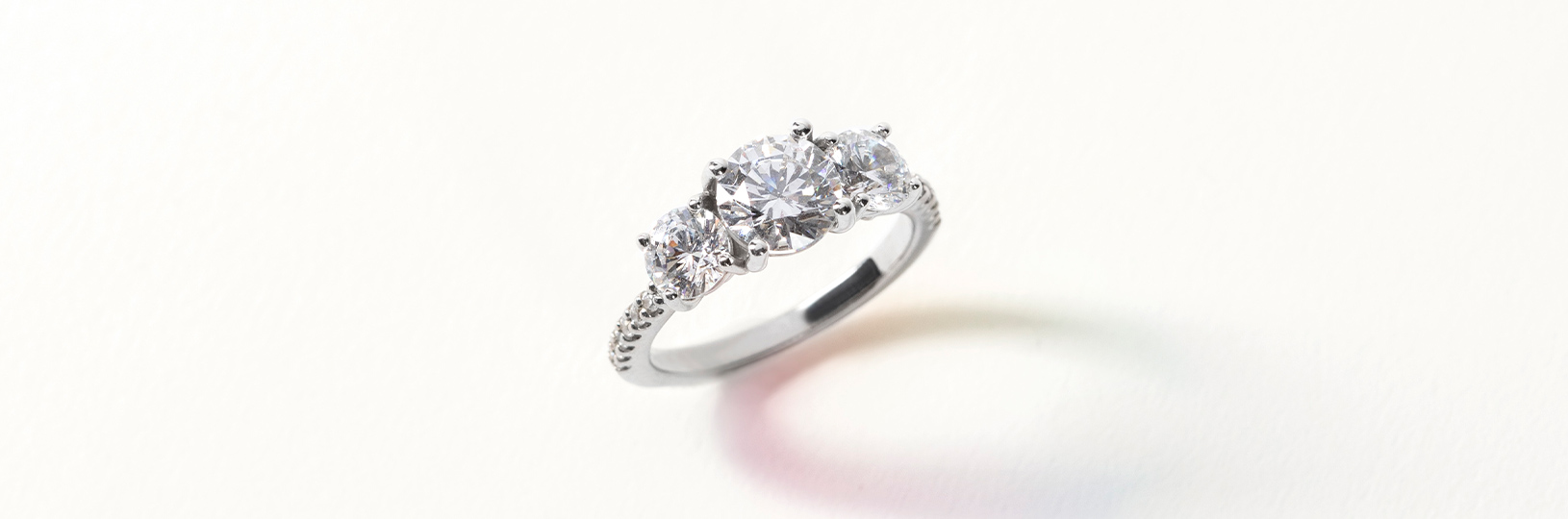Three stone accented setting featuring round cut simulated diamonds