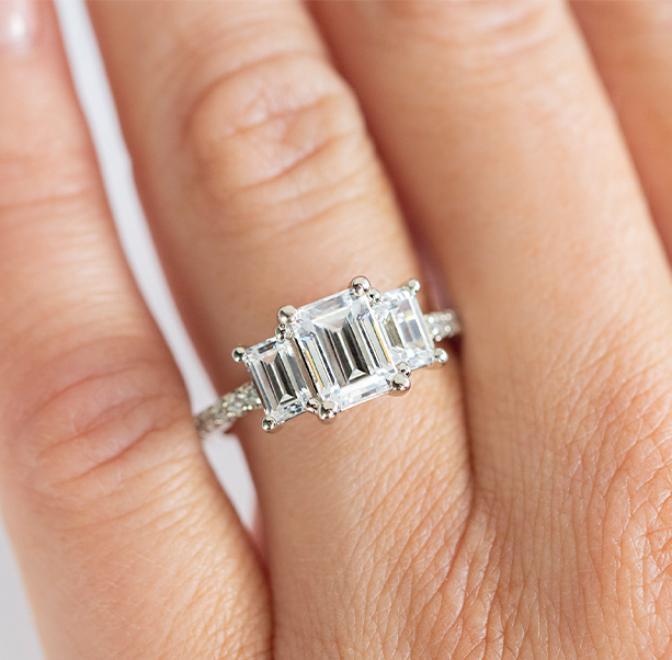 An engagement ring featuring an emerald cut center stone with two emerald cut side stones