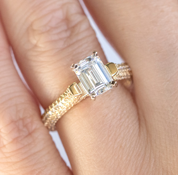 An emerald cut stone in a pave engagement ring setting