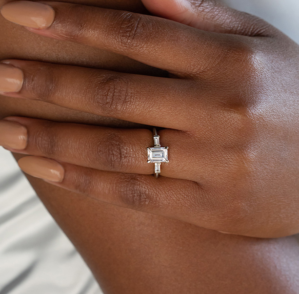 An emerald cut stone in a three stone engagement ring setting