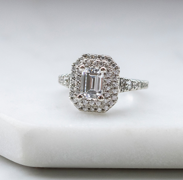 An emerald cut stone in a halo engagement ring setting