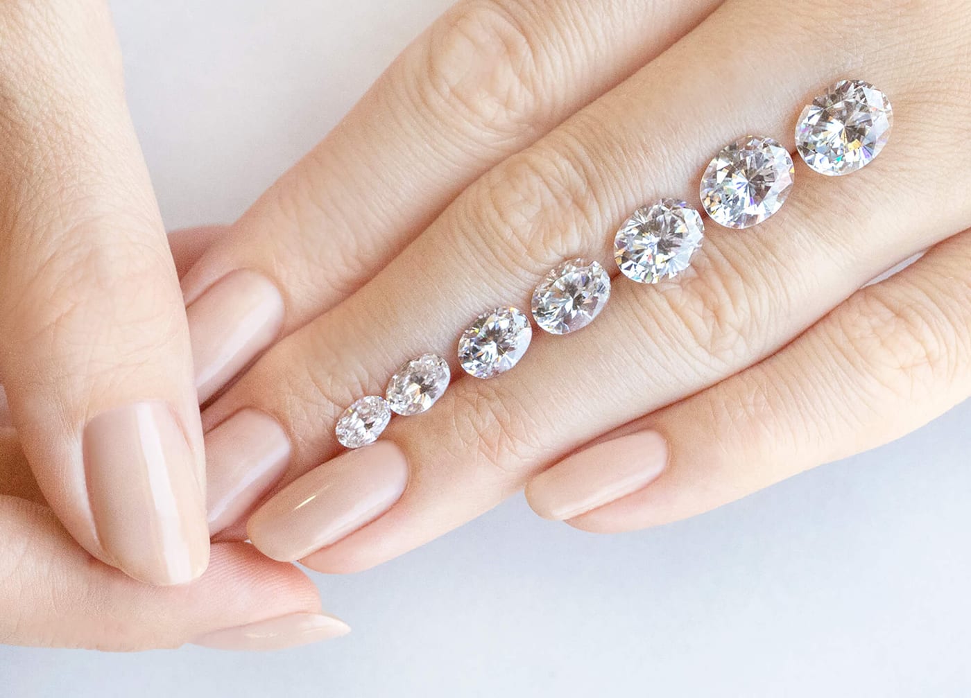 Loose Oval cut Nexus Diamond alternatives featured in varying carat weights resting on a hand.